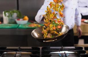 chef flipping vegetables in wok photo