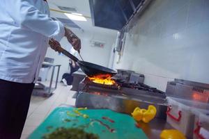 chef in hotel kitchen prepare food with fire photo