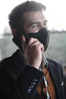 hombre de negocios con mascarilla médica de coronavirus mientras usa un teléfono inteligente foto