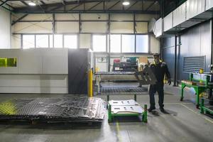 a worker working in a modern industry prepares material for processing on a cnc machine, wears a protective mask on his face due to a coronary virus pandemic photo