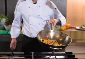 chef flipping vegetables in wok photo