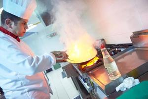 chef in hotel kitchen prepare food with fire photo