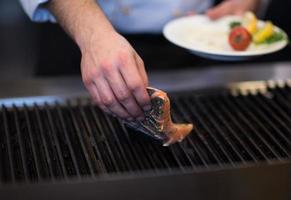 chef manos cocinando salmón a la parrilla foto