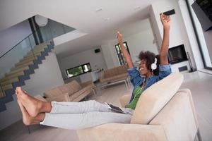 African american woman at home in chair with tablet and head phones photo