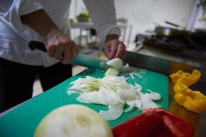 chef in hotel kitchen  slice  vegetables with knife photo