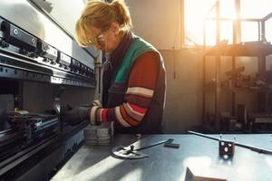 mujer que trabaja en una fábrica moderna y prepara material para una máquina cnc. foto