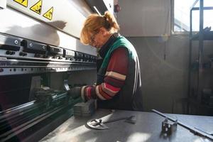 mujer que trabaja en una fábrica moderna y prepara material para una máquina cnc. foto