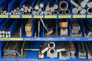 pipes, metal pieces and various metal parts for a CNC machine standing on a shelf