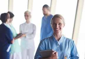 female doctor with tablet computer  standing in front of team photo