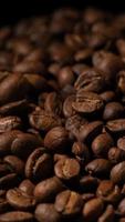 Vertical slow motion of roasted coffee beans falling. Organic coffee seeds. video