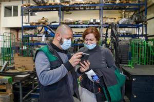 Industrial workers with face masks protected against corona virus discussing about production in factory. People working during COVID-19 pandemic. photo