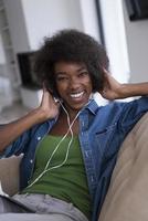 African american woman at home in chair with tablet and head phones photo