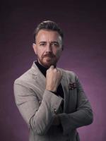 Portrait of a stylish elegant senior businessman with a beard and casual business clothes in photo studio isolated on dark background gesturing with hands