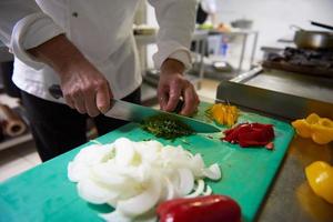 chef in hotel kitchen  slice  vegetables with knife photo