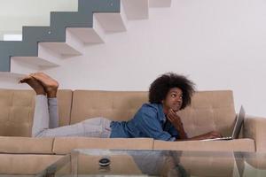 African American woman using laptop on sofa photo