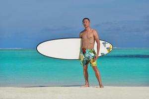 hombre con tabla de surf en la playa foto