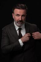 retrato de un elegante hombre de negocios de alto nivel con barba y ropa informal de negocios en un estudio fotográfico que ajusta el traje foto