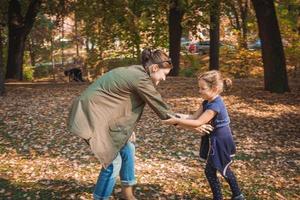 feliz madre e hija jugando en el parque de otoño. foto