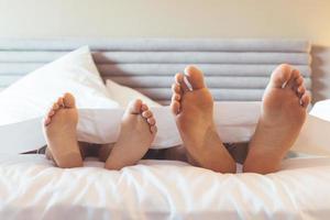Feet of father and child under bed sheet. photo