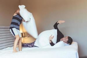 Father and son fighting with pillows in the bedroom. photo