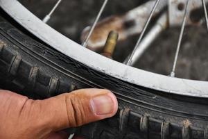 el neumático de la bicicleta estaba desinflado y estacionado en el pavimento, el reparador lo está revisando. enfoque suave y selectivo en el neumático. foto