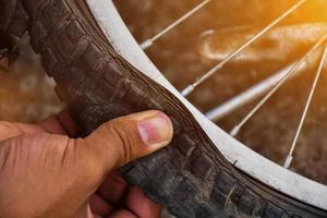 el neumático de la bicicleta estaba desinflado y estacionado en el pavimento, el reparador lo está revisando. enfoque suave y selectivo en el neumático. foto