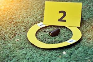 Pistol's bullet shells and yellow number paper sign on floor, concept for keeping physical evidences of the use of pistols, guns and bullet shells at the point of the murder. photo