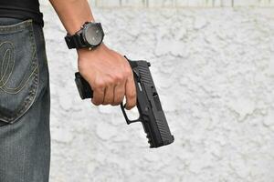 Pistol holding in hands of gunman at the shooting club, soft and selective focus on pistol, concept for shooting sport, bodyguard, security training, mafias, gangsters and self protections.
