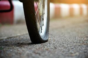 Closeup flat rear wheel of the bike which parked on pavement, soft and selective focus. photo