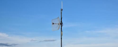 Outdoor internet wifi receiver and repeater antenna on the roof of the building with clear bluesky background. photo