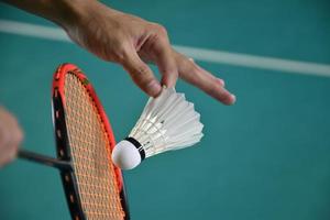 Badminton player holds racket and white cream shuttlecock in front of the net before serving it to another side of the court. photo