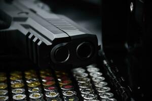 pistola automática negra de 9 mm y balas sobre fondo de cuero negro, enfoque selectivo y suave. foto