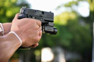 Pistol holding in hands of gunman at the shooting club, soft and selective focus on pistol, concept for shooting sport, bodyguard, security training, mafias, gangsters and self protections.