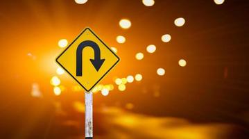 Right u-turn sign on pole, streetlights bokeh background. Concept for traffic sign at night. photo