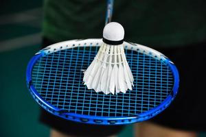 Cream white badminton shuttlecock and racket on floor in indoor badminton court, copy space, soft and selective focus on shuttlecocks. photo