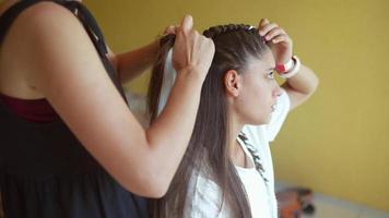 Girls braiding hair with a white strand of hair video