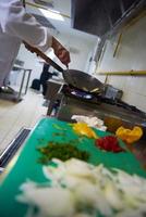 chef en la cocina del hotel prepara comida con fuego foto