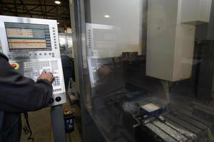 close up a worker hand or engineer introducing a program into a modern CNC machine. The concept of industry and engineering. photo