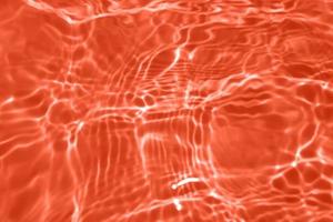 Defocus blurred transparent orange colored clear calm water surface texture with splash, bubble. Shining orange water ripple background. Surface of water in swimming pool. Orange bubble water, splash. photo