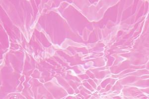 Defocus blurred transparent pink colored clear calm water surface texture with splash, bubble. Shining pink water ripple background. Surface of water in swimming pool. Tropical pink water color flow. photo