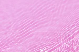 Defocus blurred transparent pink colored clear calm water surface texture with splash, bubble. Shining pink water ripple background. Surface of water in swimming pool. Tropical pink water color flow. photo