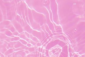 Defocus blurred transparent pink colored clear calm water surface texture with splash, bubble. Shining pink water ripple background. Surface of water in swimming pool. Tropical pink water color flow. photo