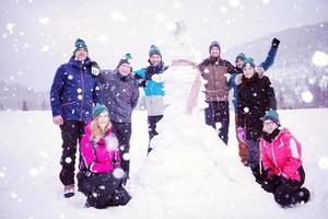 group portait of young people posing with snowman photo