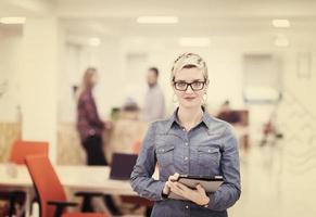 retrato, de, joven, mujer de negocios, en, oficina, con, equipo, en, plano de fondo foto