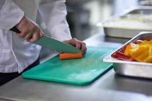 chef in hotel kitchen  slice  vegetables with knife photo