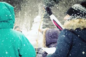 young people measuring the height of finished snowman photo