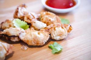 Crispy deep-fried wontons on wooden plate serve with sweet chilli sauce. photo