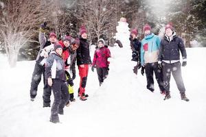 retrato de grupo de jóvenes posando con muñeco de nieve foto