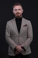 portrait of a stylish elegant businessman looking at camera in photo studio on dark background with hard light