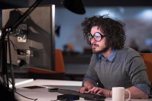 hombre trabajando en una computadora en una oficina de inicio oscura foto